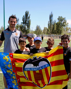 Entrenador y niños sosteniendo una bandera de Valencia CF
